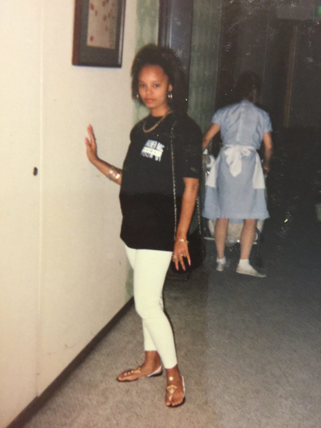 Sonya posing in a hallway in a black tee and white pants