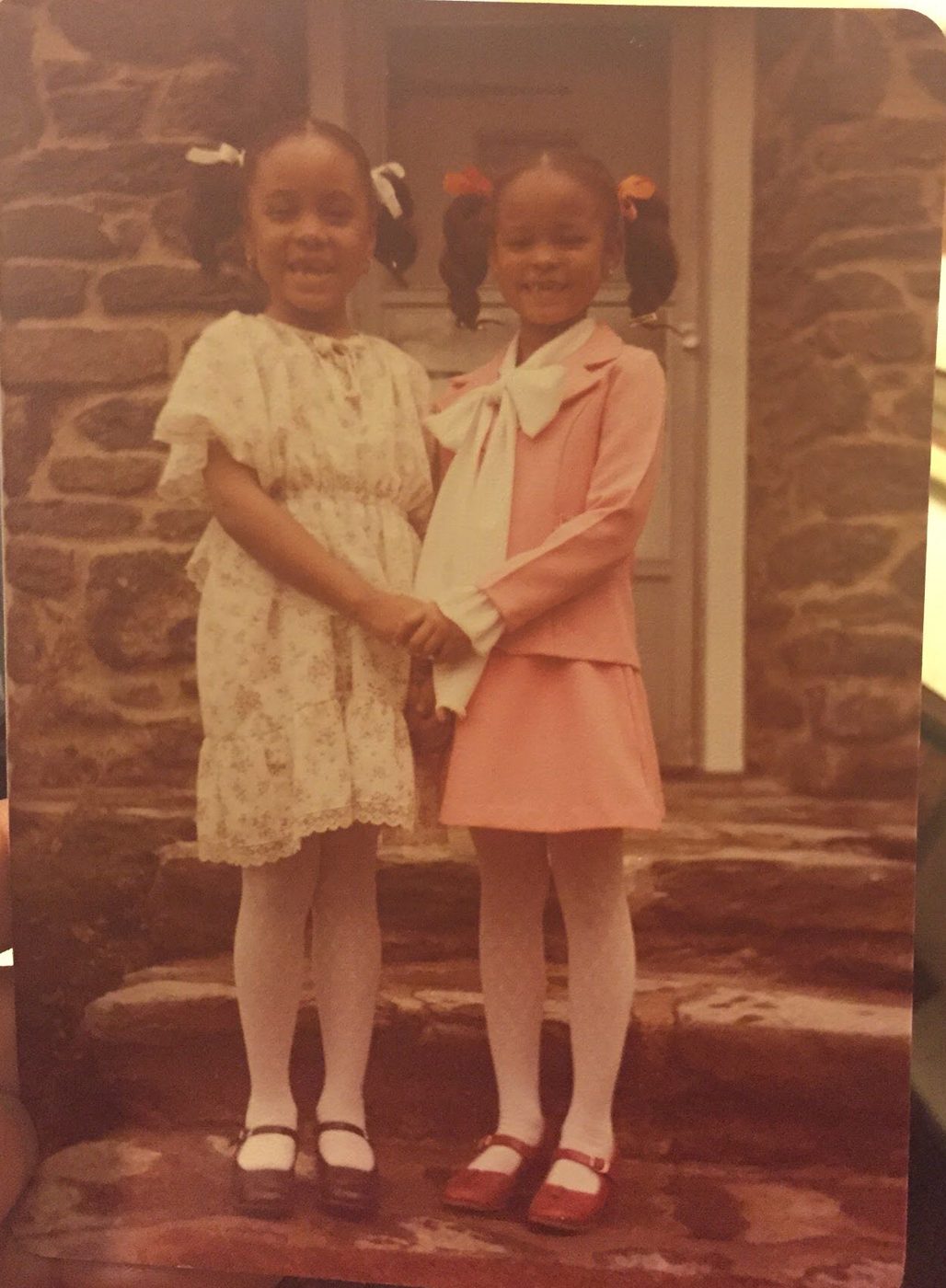 Sonya as a young girl holding hands with a friend on stone steps