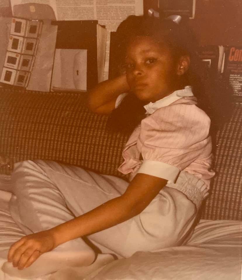 Sonya as a girl, relaxing on a bed with her head on her hand
