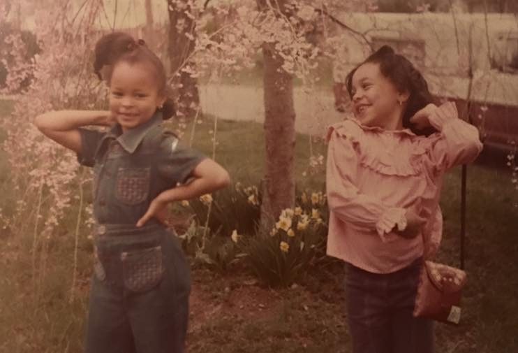Sonya as a young girl posing with a friend among spring blossoms