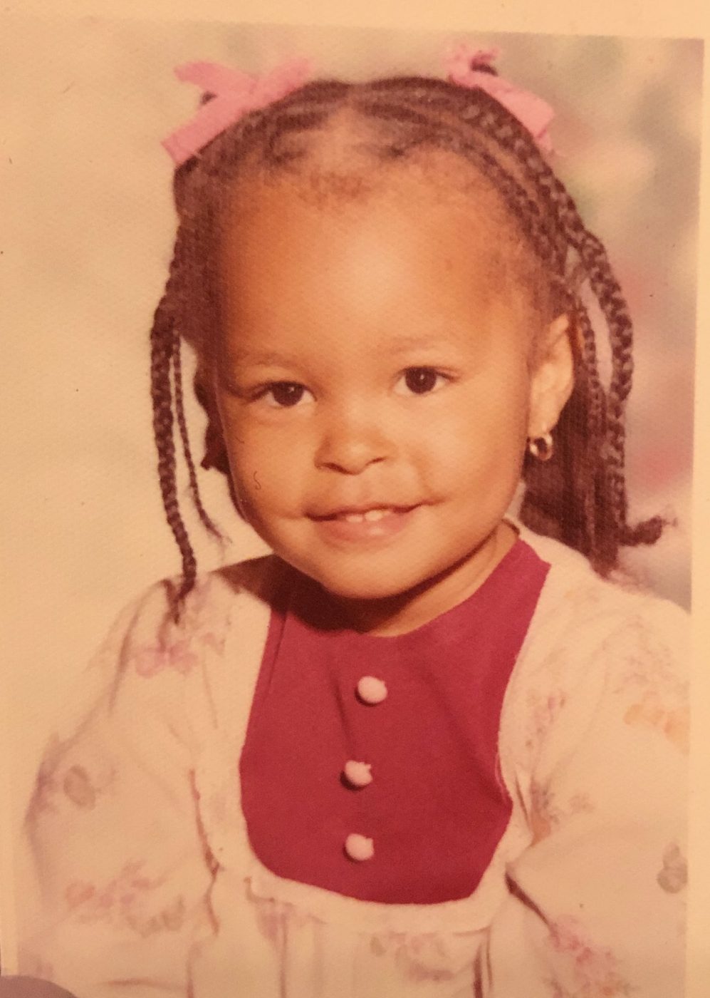 Sonya as a toddler, school portrait with braids and pink bows