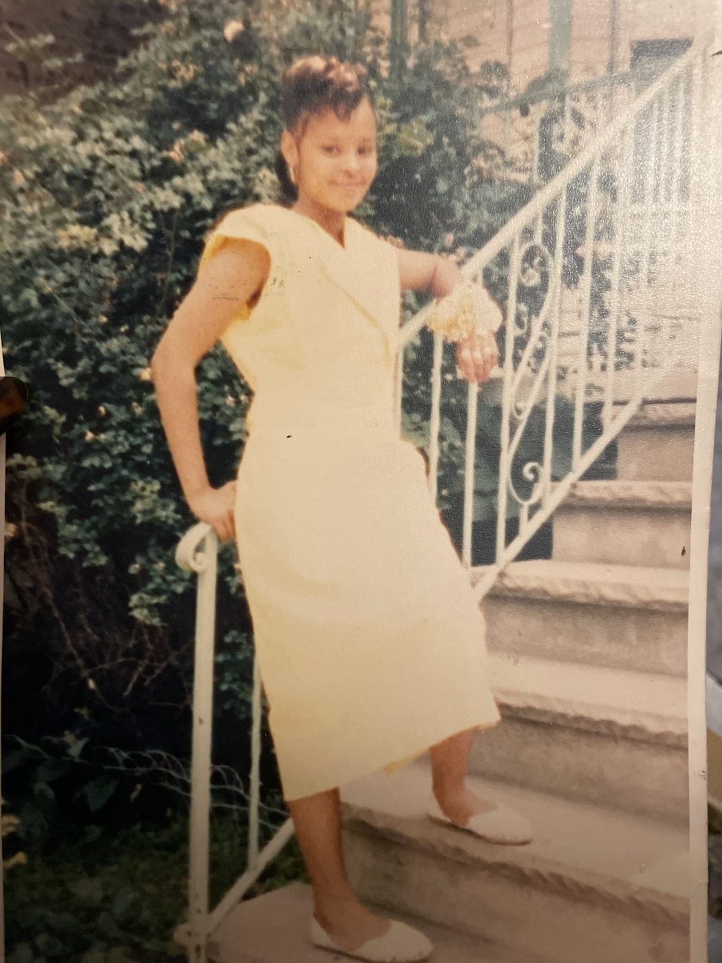 Sonya in a pale yellow dress posing on outdoor stairs
